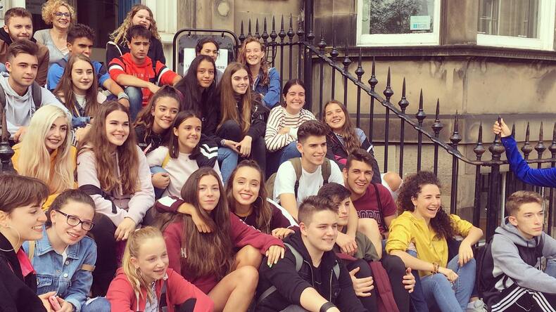 Alumnos felices delante del edificio de la escuela